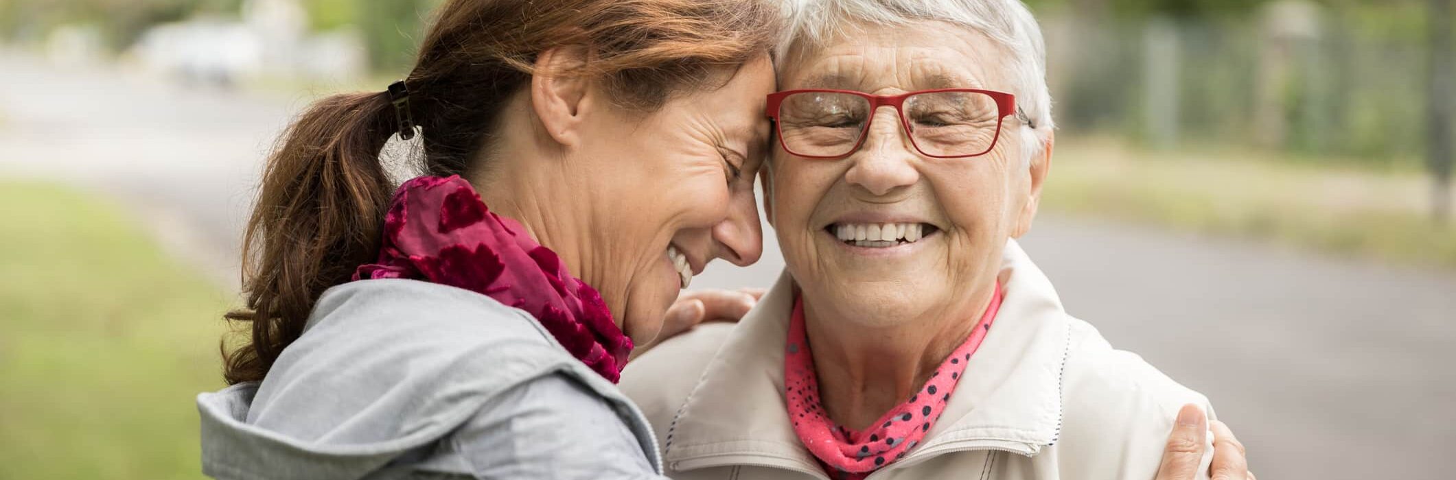 Happy senior woman and caregiver walking outdoors